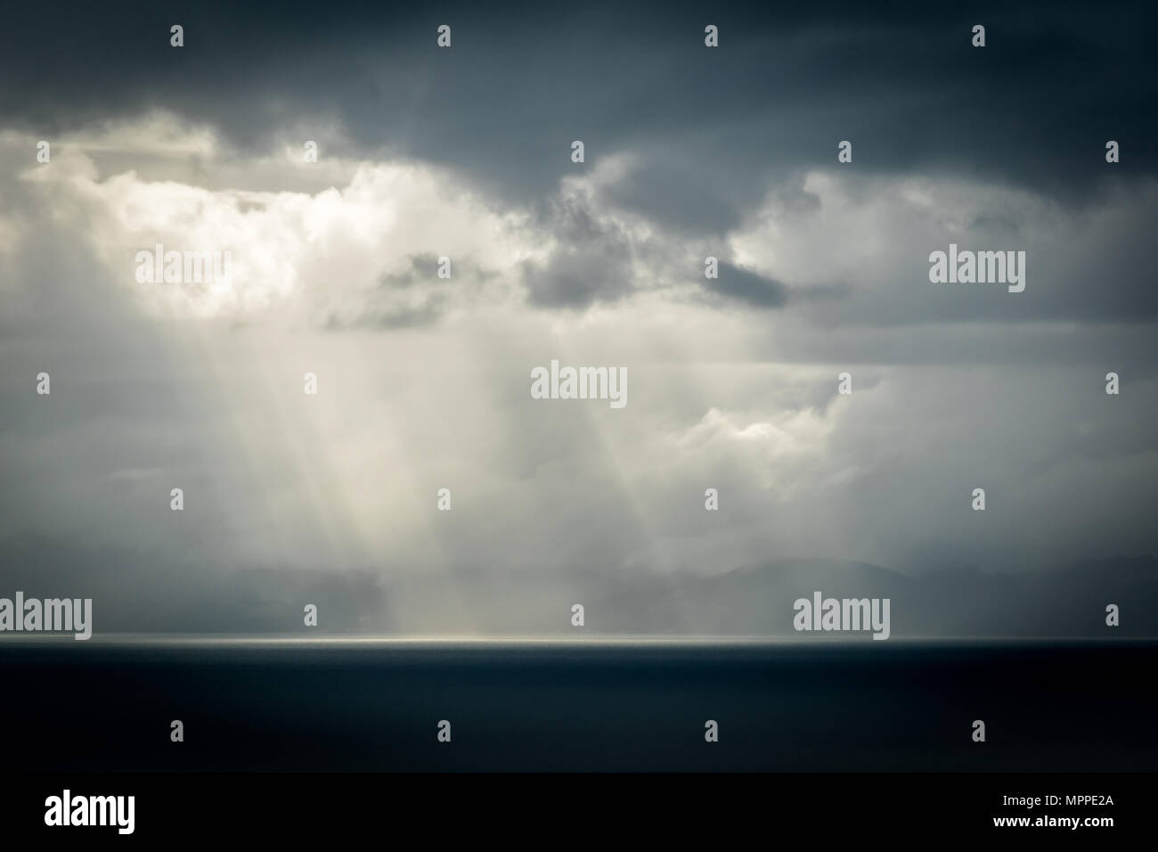 Sun rays through some stormy clouds over the ocean Stock Photo - Alamy