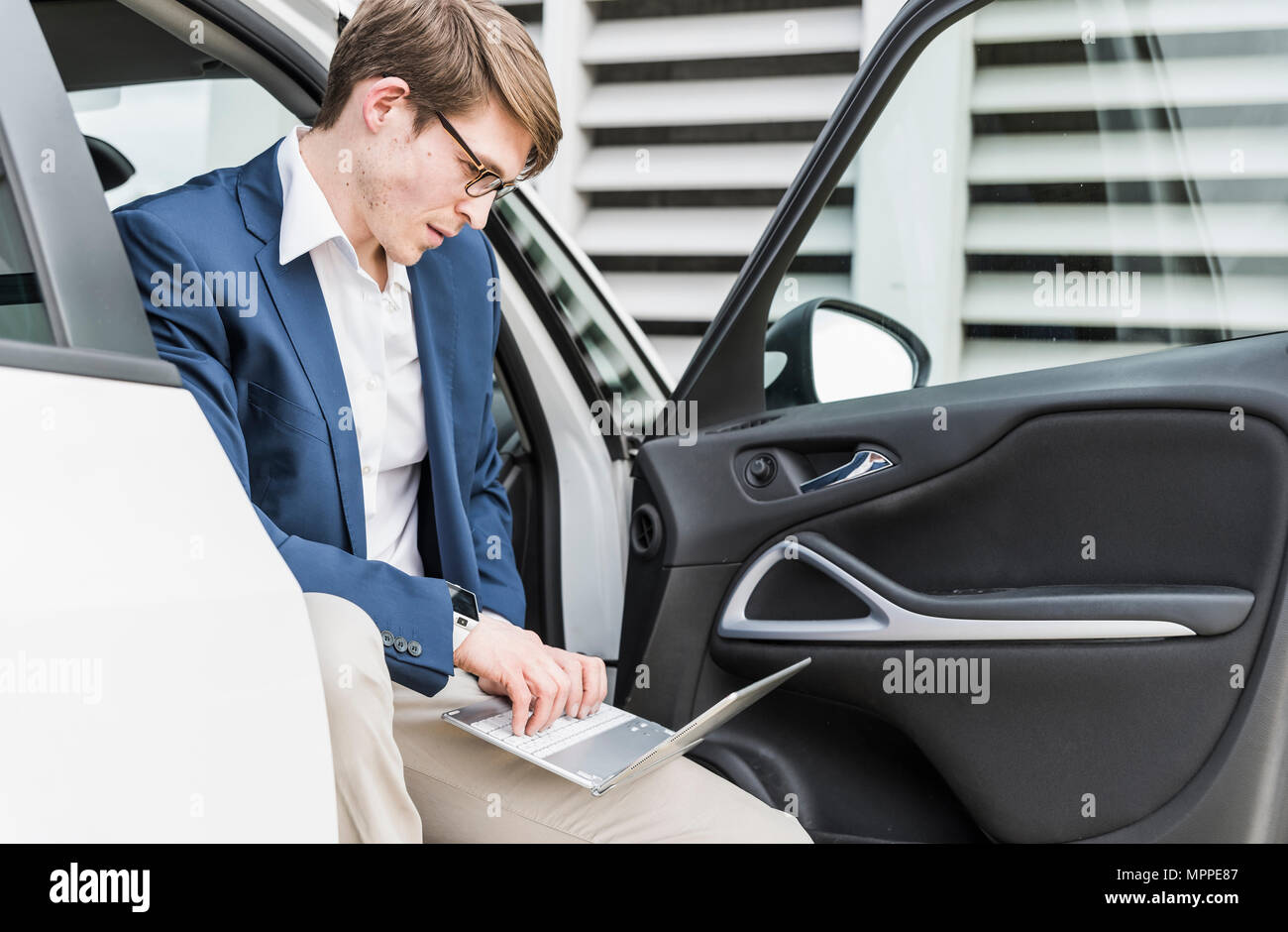 Businessman sitting in car using laptop Stock Photo