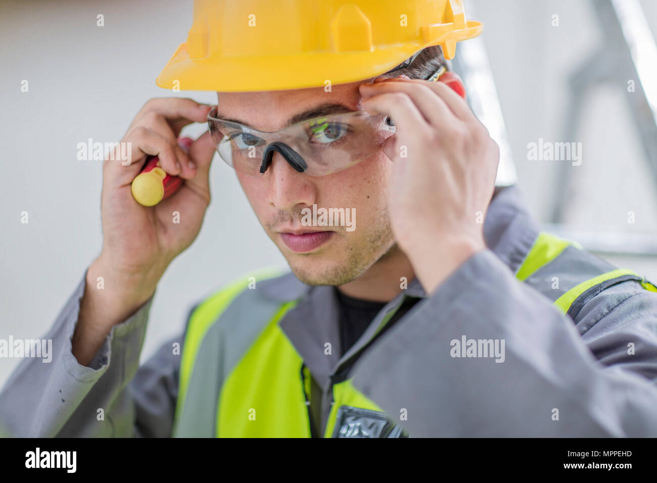 Electrician putting on protective glasses Stock Photo