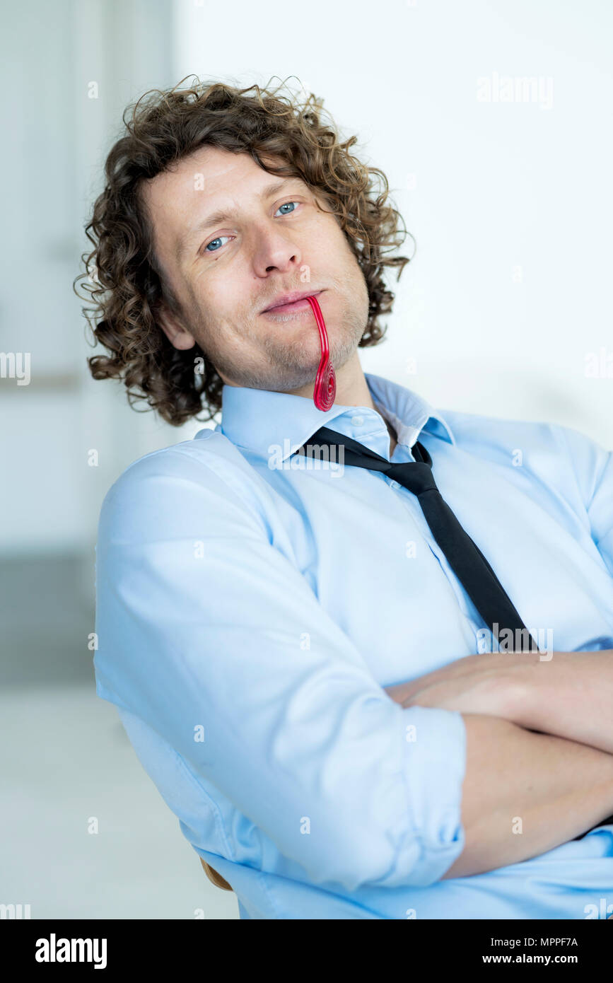 Easygoing businessman sitting in office, chewing sweets Stock Photo
