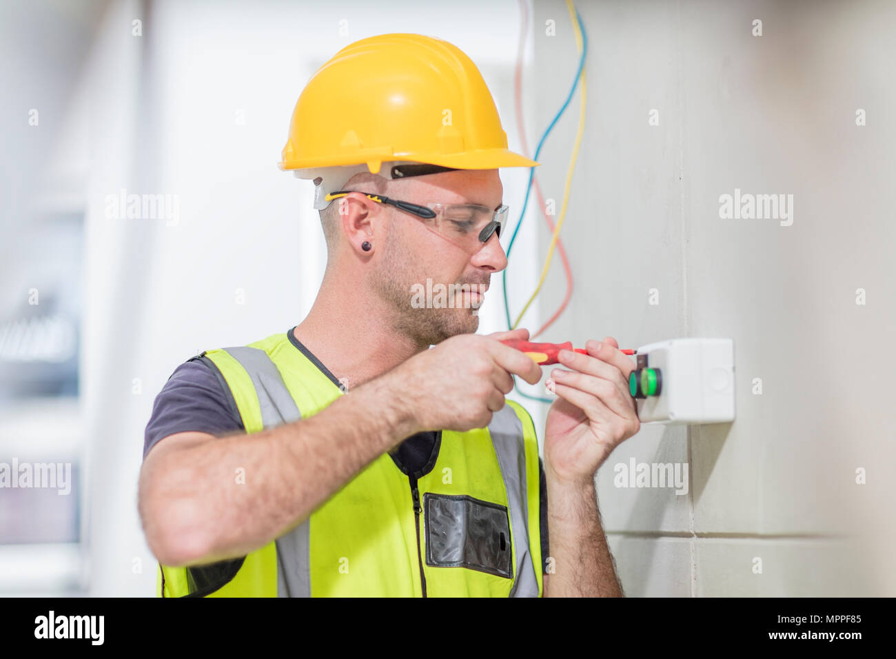 Electrician screwing in wire on construction site Stock Photo