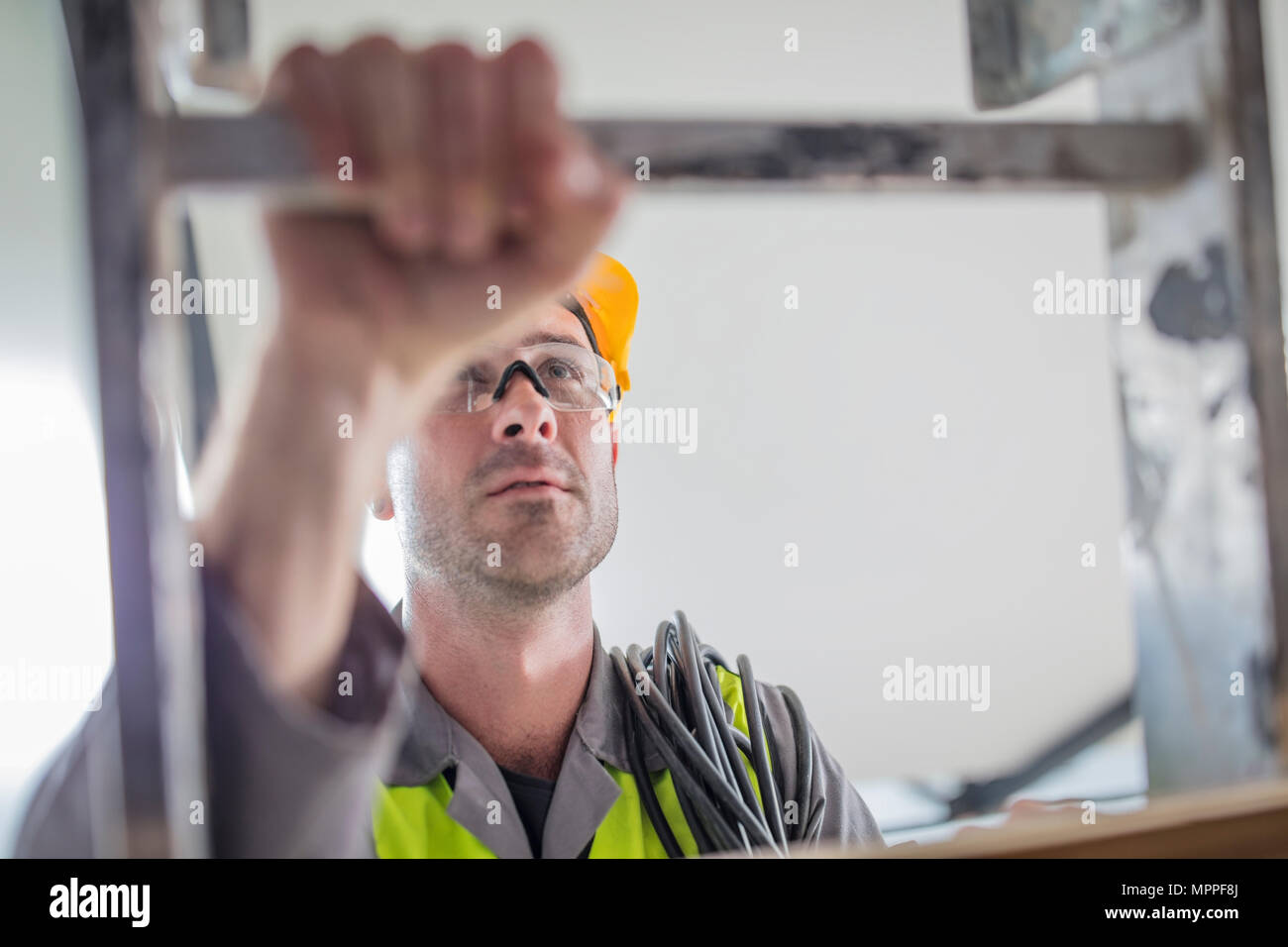 Close-up of construction worker climbing ladder Stock Photo