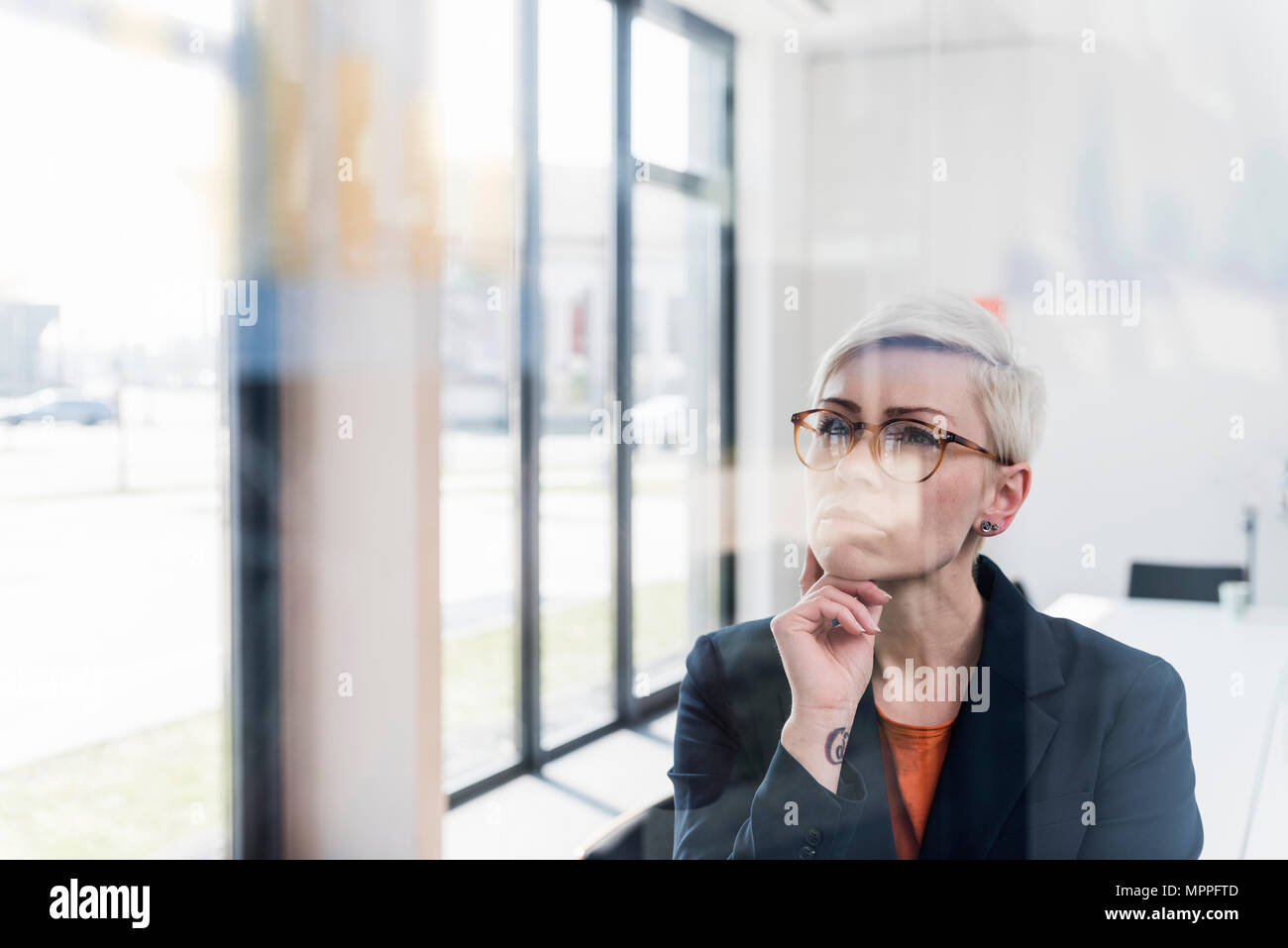 Focused businesswoman looking at glass pane in office Stock Photo