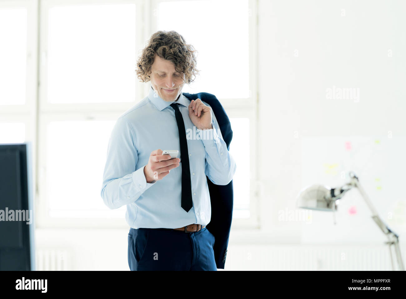Smart businessman standing in office, using mobile phone Stock Photo