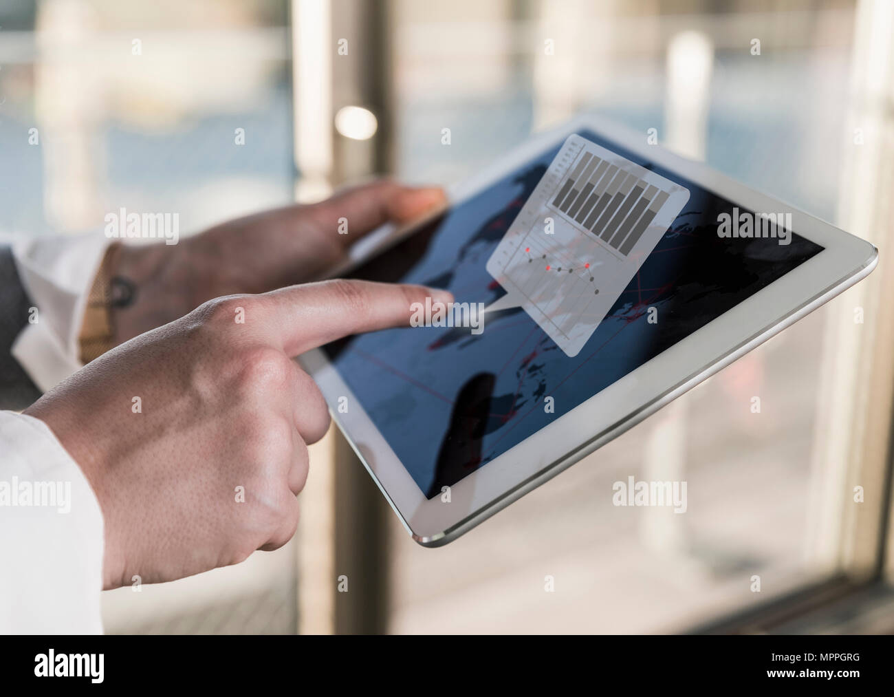 Woman using tablet in office with data emerging from screen Stock Photo
