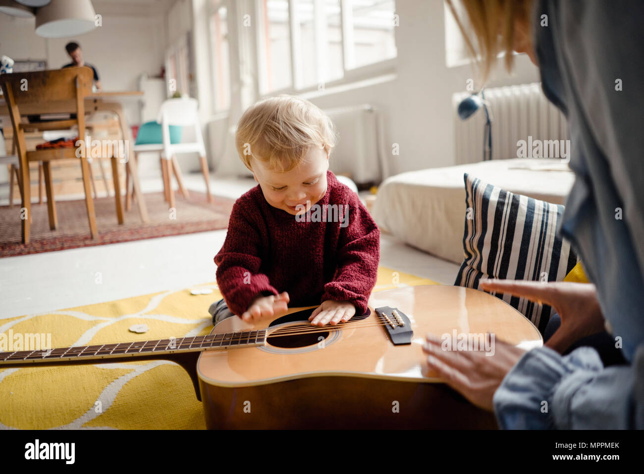 Baby boy exploring a guitar with his mother Stock Photo