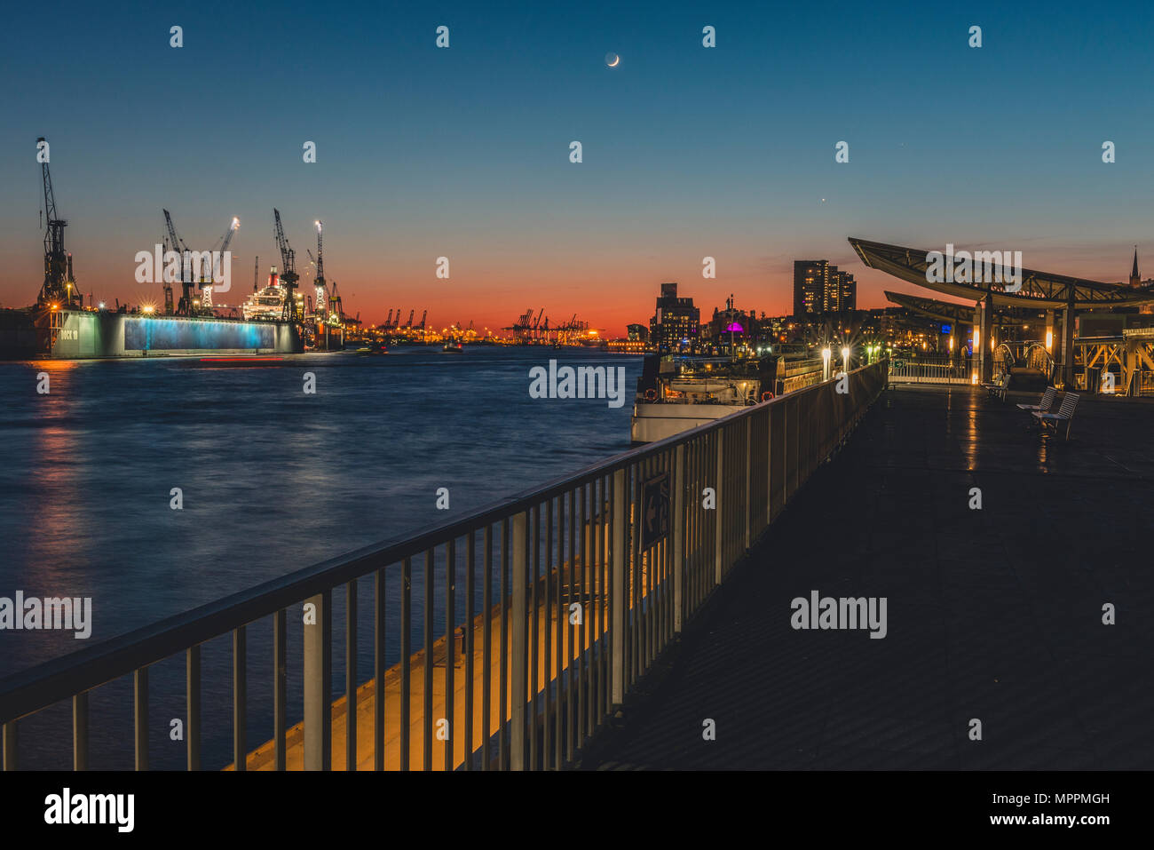 Germany, Hamburg, St. Pauli Landing Stages, Elbe river, docks in the evening light with crescent Stock Photo