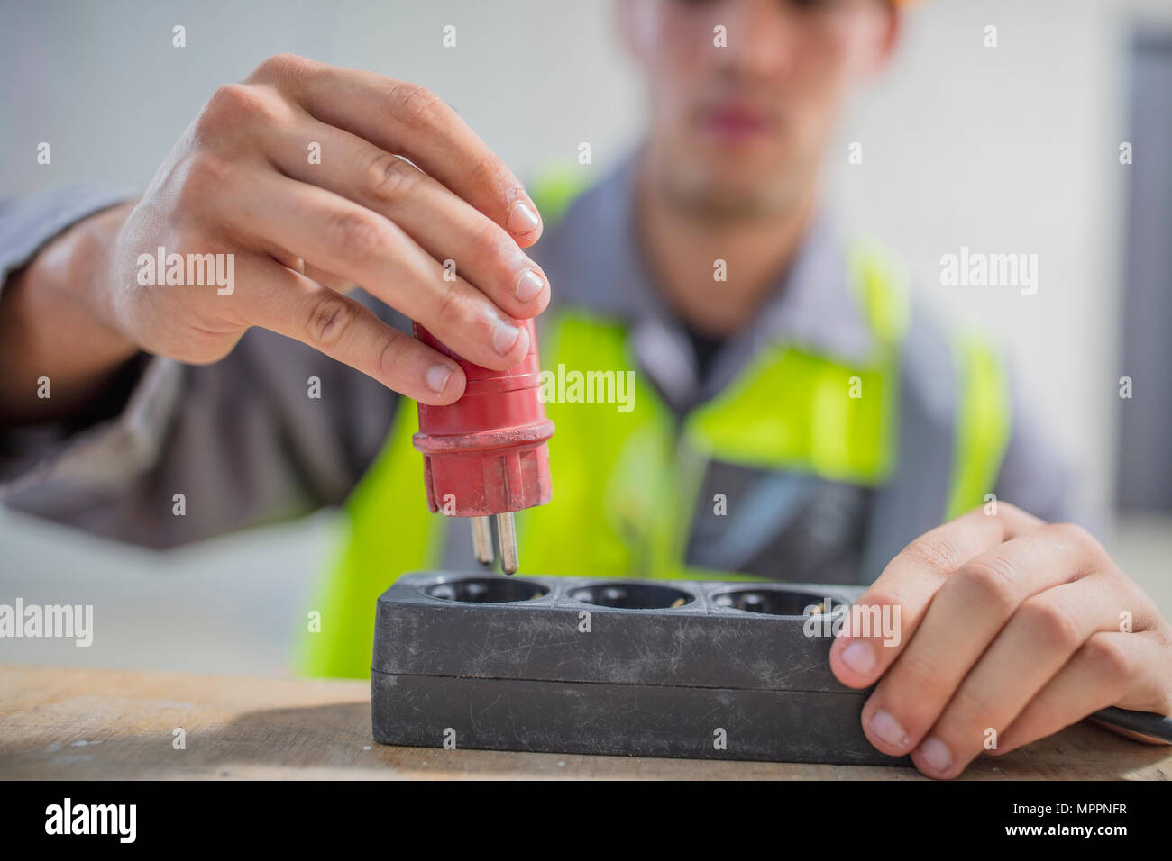 Close-up of electrician putting plug into power strip Stock Photo