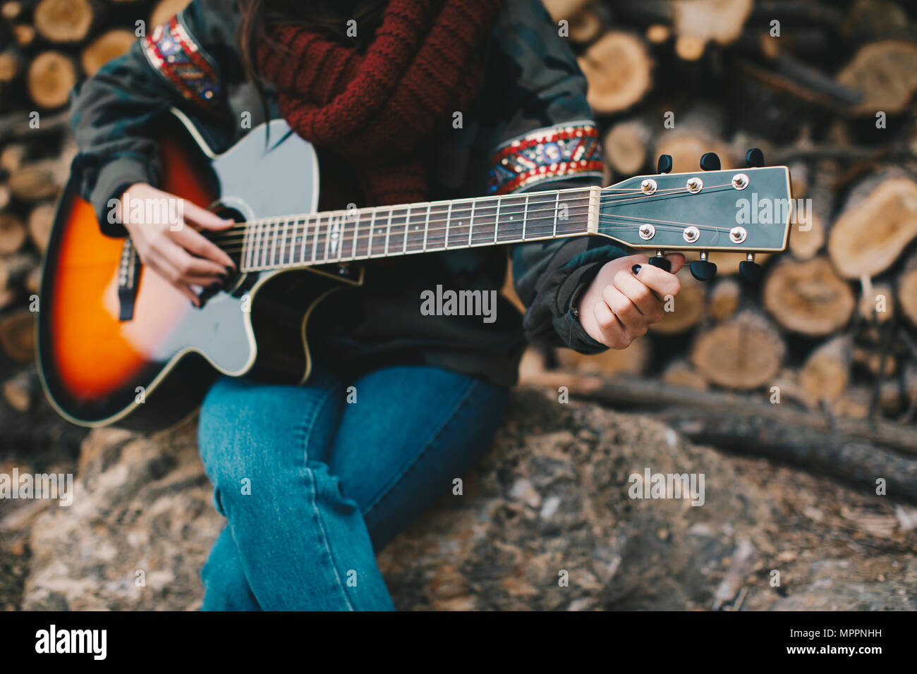 Young woman tuning guitar outdoors, partial view Stock Photo