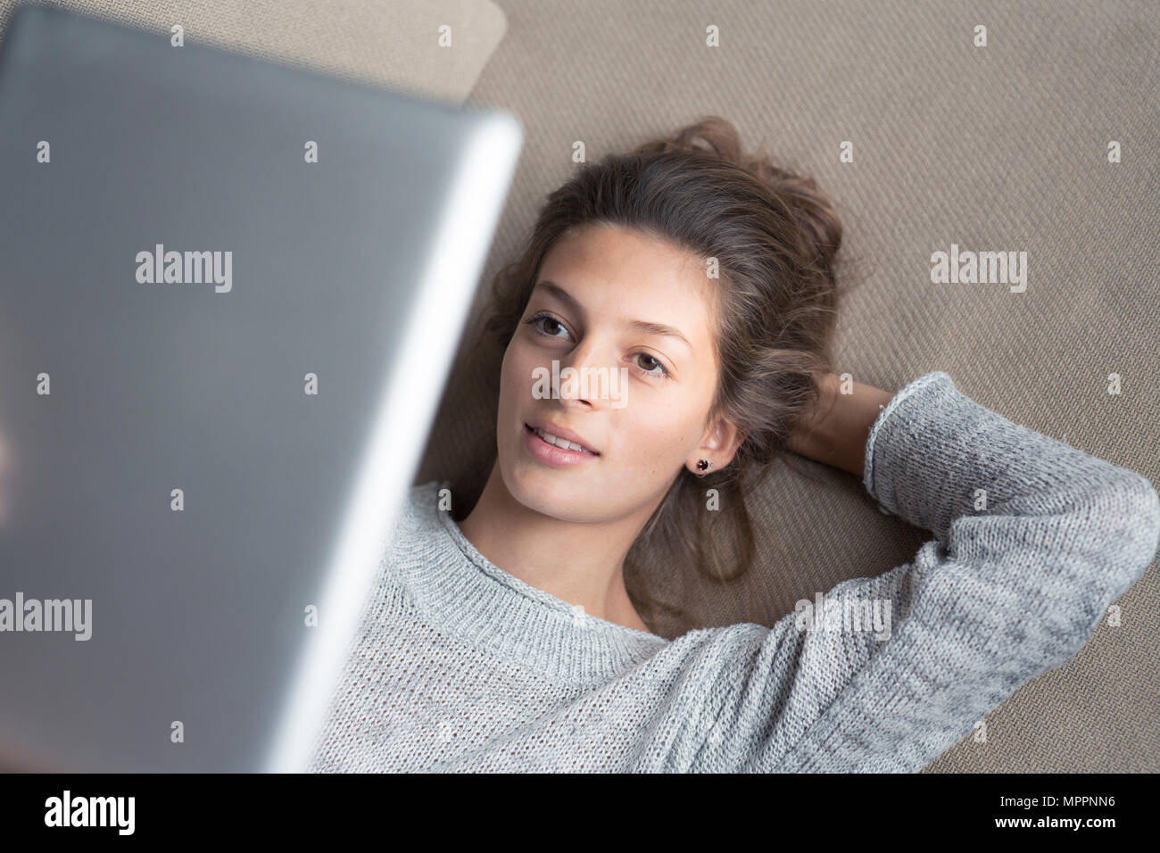 Woman lying on couch using tablet Stock Photo