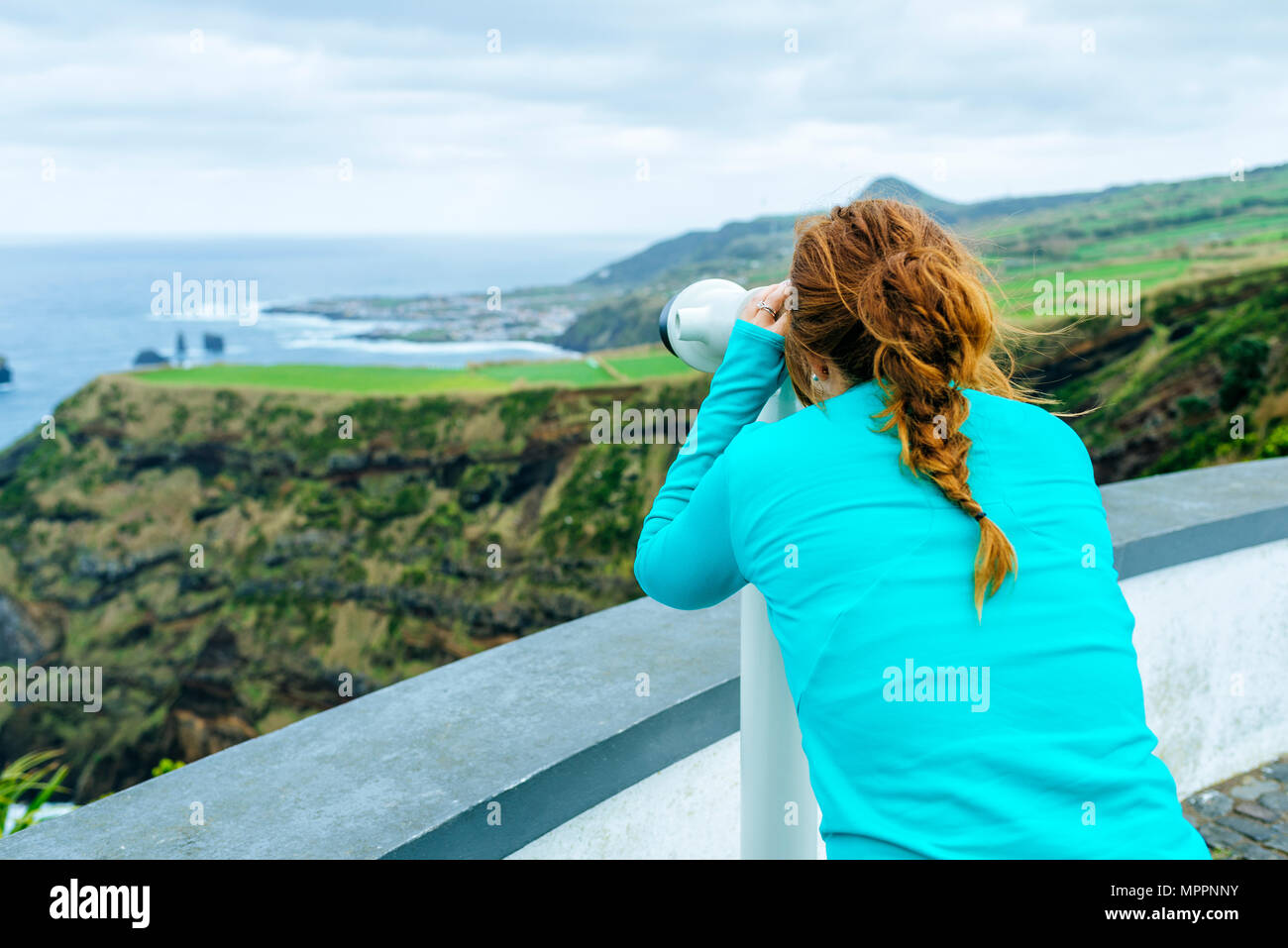 Azores, Sao Miguel, Woman looking through a tourist binoculars towards the sea Stock Photo