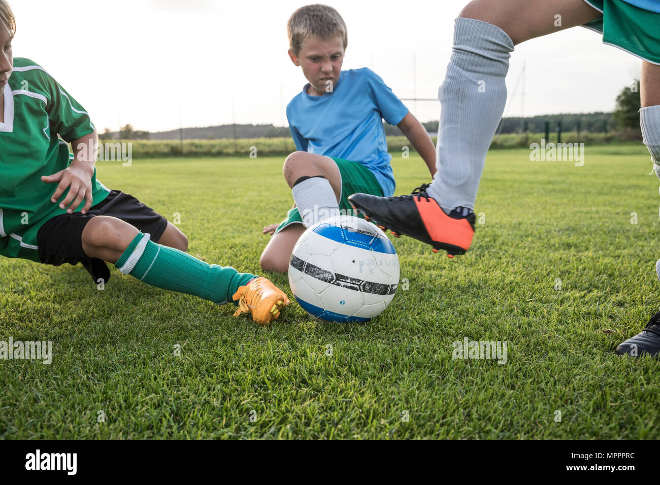 Young football players tackling football ground hi-res stock