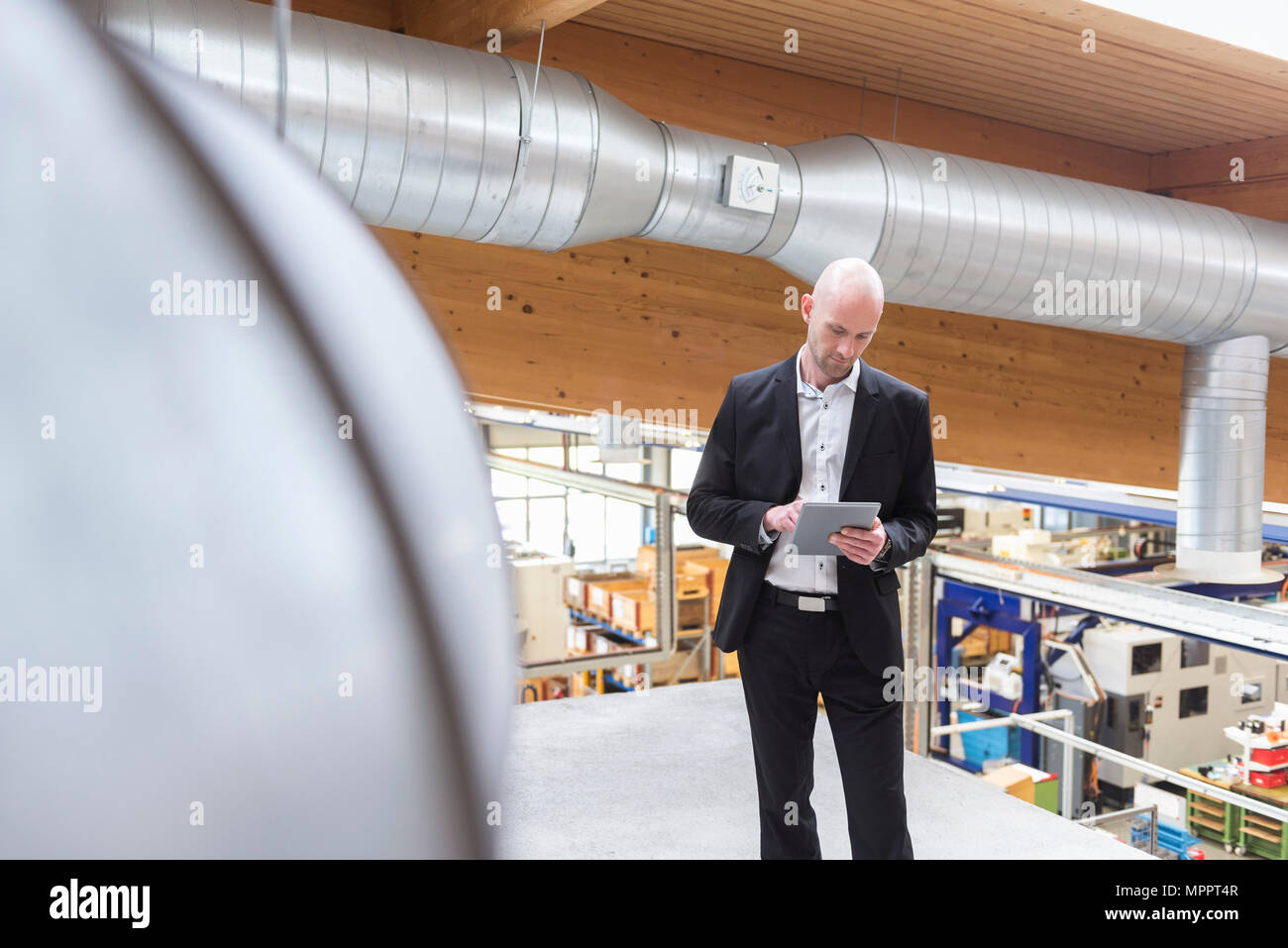Businessman using tablet in modern factory Stock Photo
