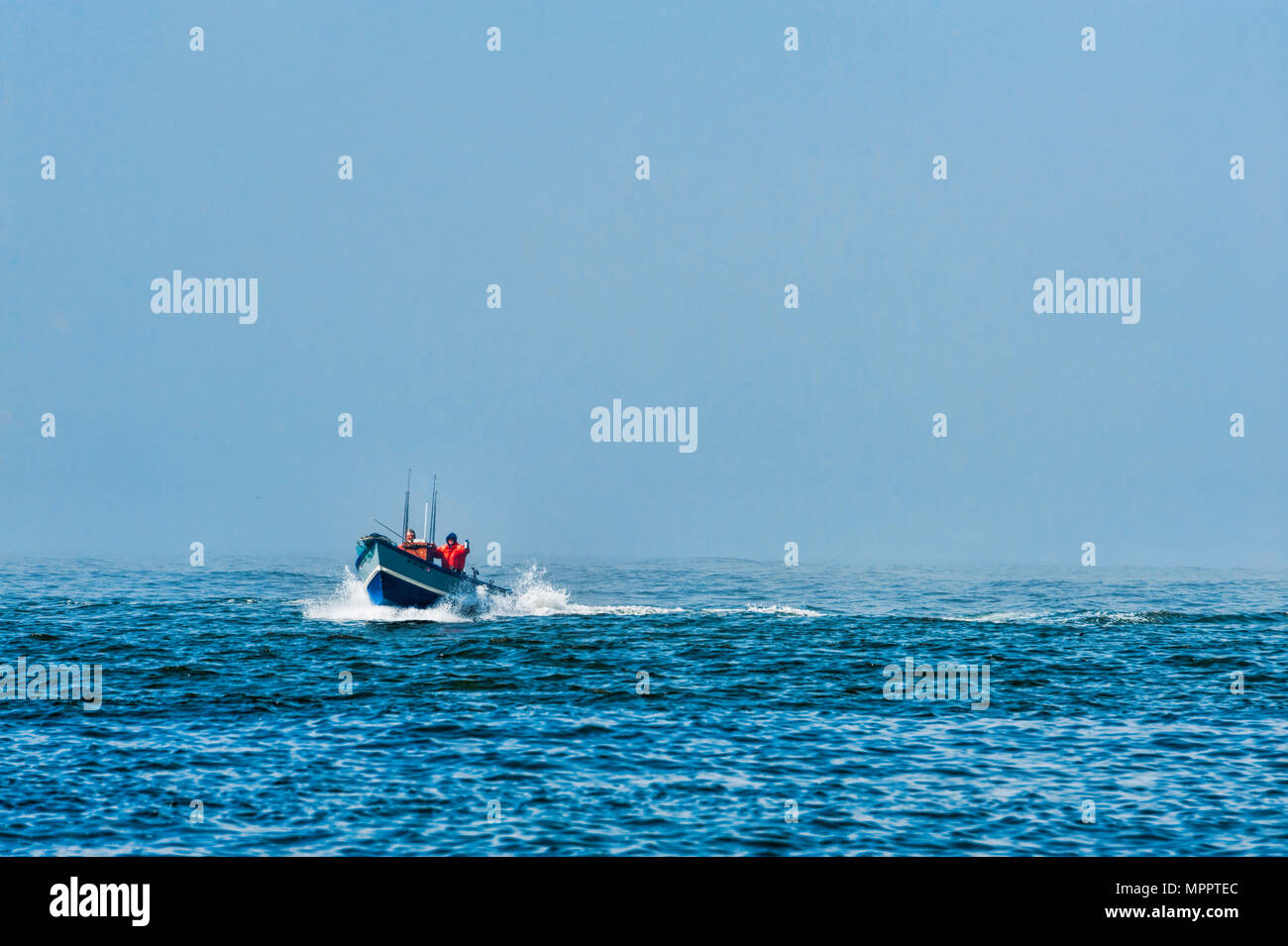 Pacific City, Oregon, USA - July 2, 2015: A dory boat captain blows a canstier horn announcing his presents as he comes in from the foggy sea to land  Stock Photo