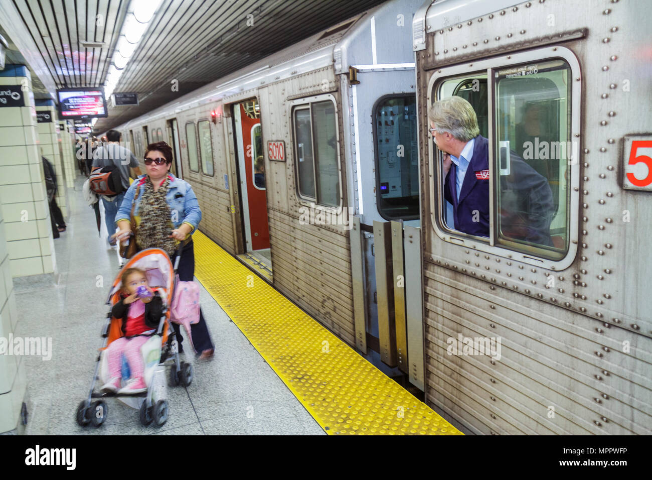 Toronto Canada,College Station,Yonge Yellow Line,TTC,Transit Commussion subway train,man male woman,girl mother child stroller conductor platform Stock Photo