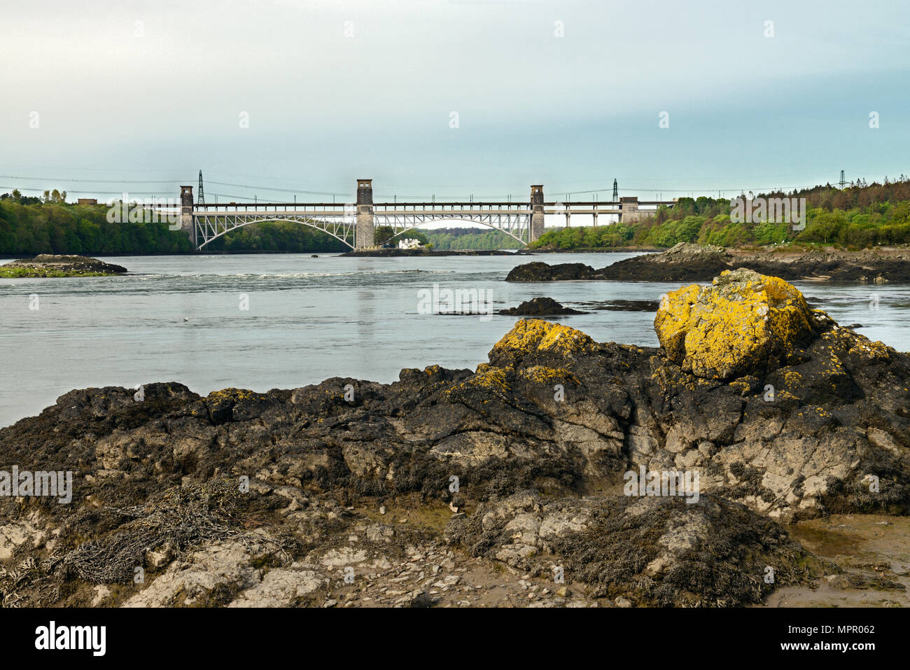 Menai Strait is a narrow stretch of sea water that separates the island of Anglesey from mainland Wales and here includes the Britannia Bridge. Stock Photo