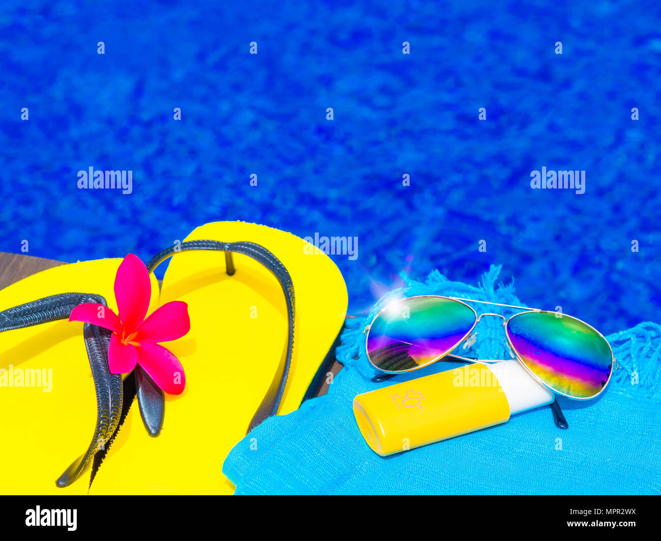 Bottle of sunscreen, hat and sunglasses next to swimming pool in hotel with  palms on background Stock Photo - Alamy