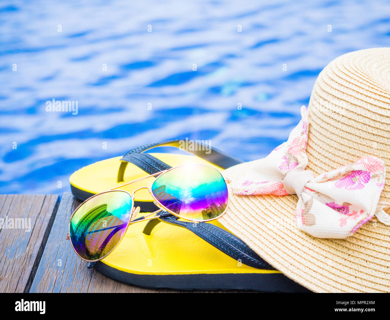Summer hat with sunglasses and flip flops by the swimming pool ...