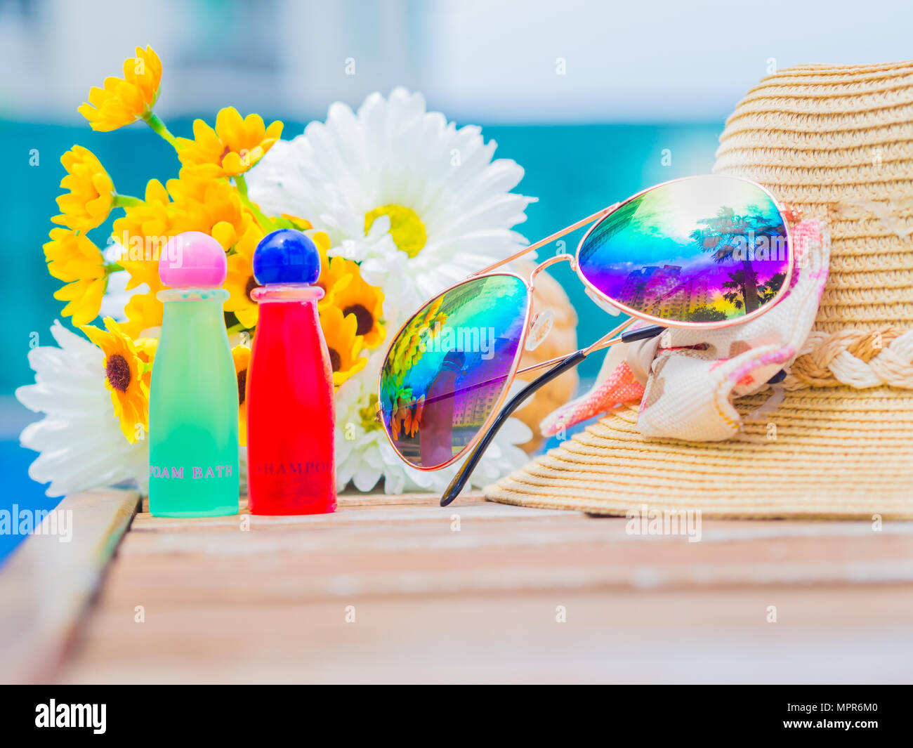 Sunglasses with summer hat and flowers by the swimming pool. Vacation ...