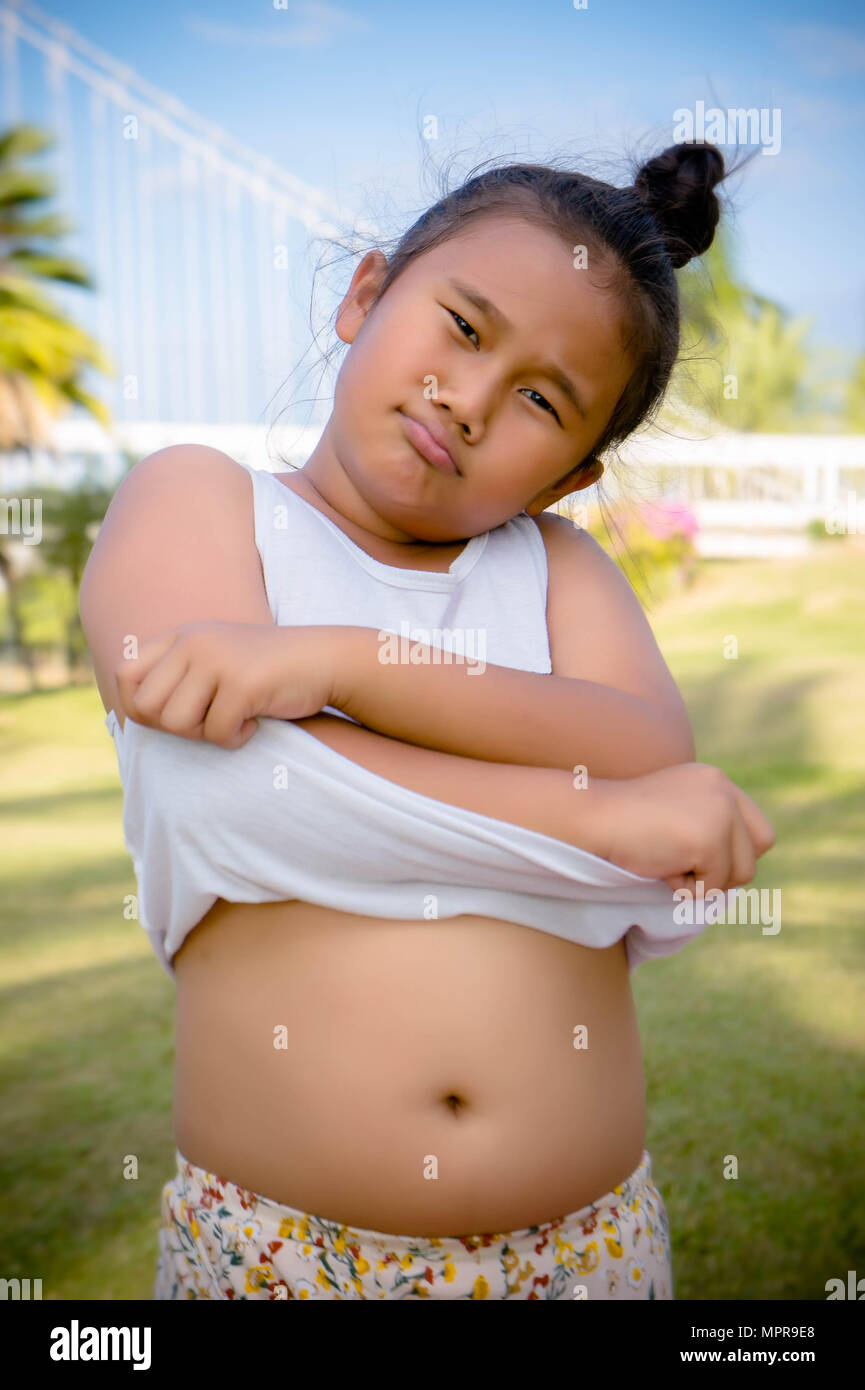 Fat girl kid show big Belly, paunch , girl like eat Stock Photo