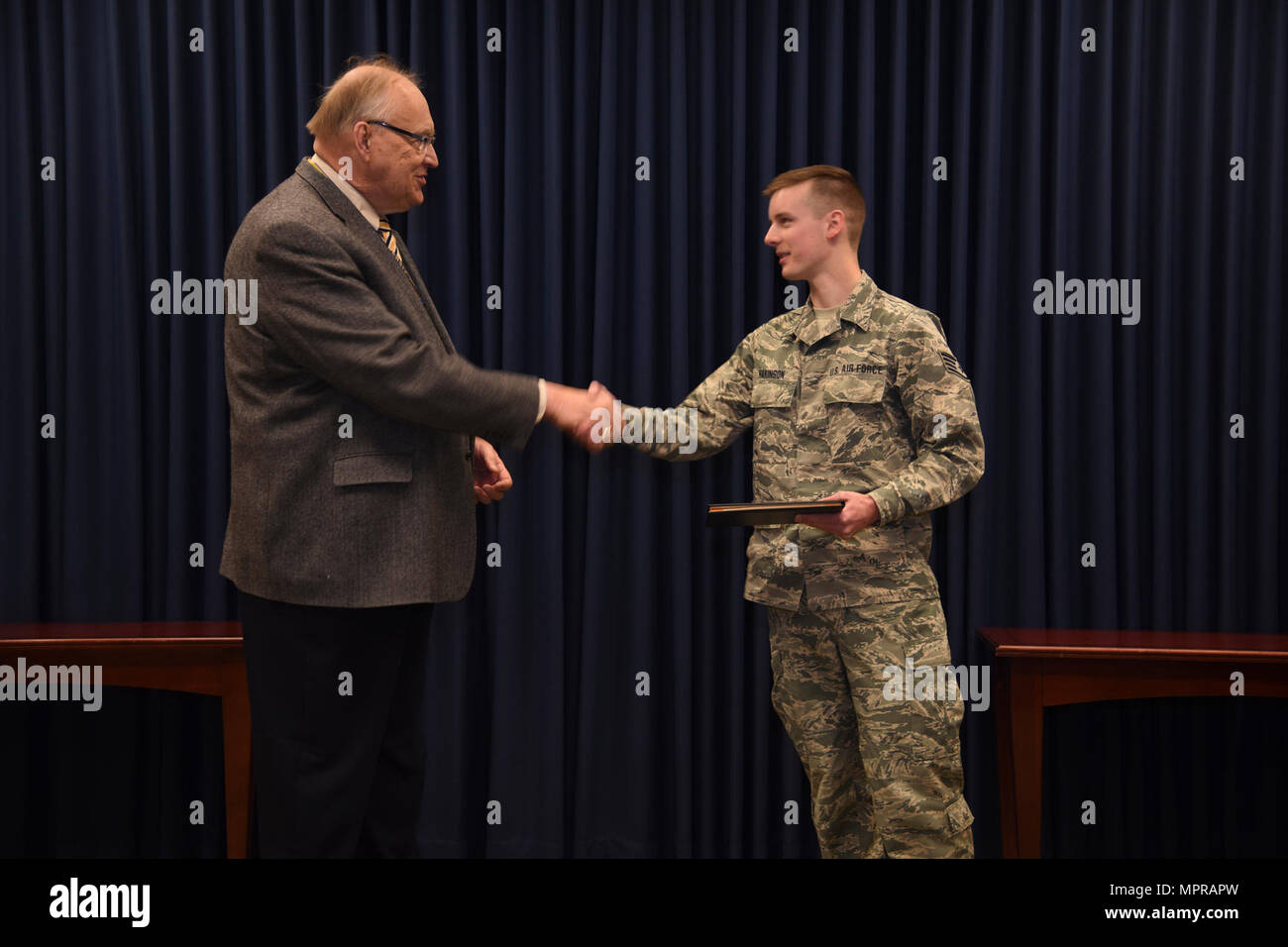 Sioux Falls, S.D. - Staff Sgt. Zac Hakinson, 114th Communication Flight information technology specialist, receives his collage diploma from Dr. Richard Hanson, Dakota State Univeristy Provost and Vice President for Academic Affairs, April 11, 2017, Joe Foss Field, S.D. Hakinson recieved his diploma prior to deploying for a Reserve Component Period. Stock Photo