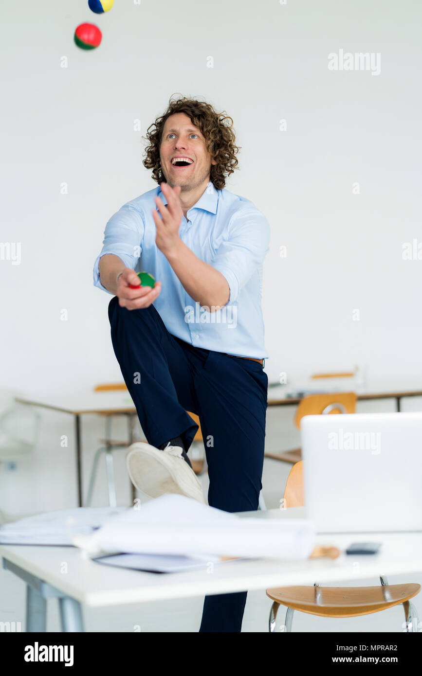 Laughing businessman juggling balls in his office Stock Photo - Alamy