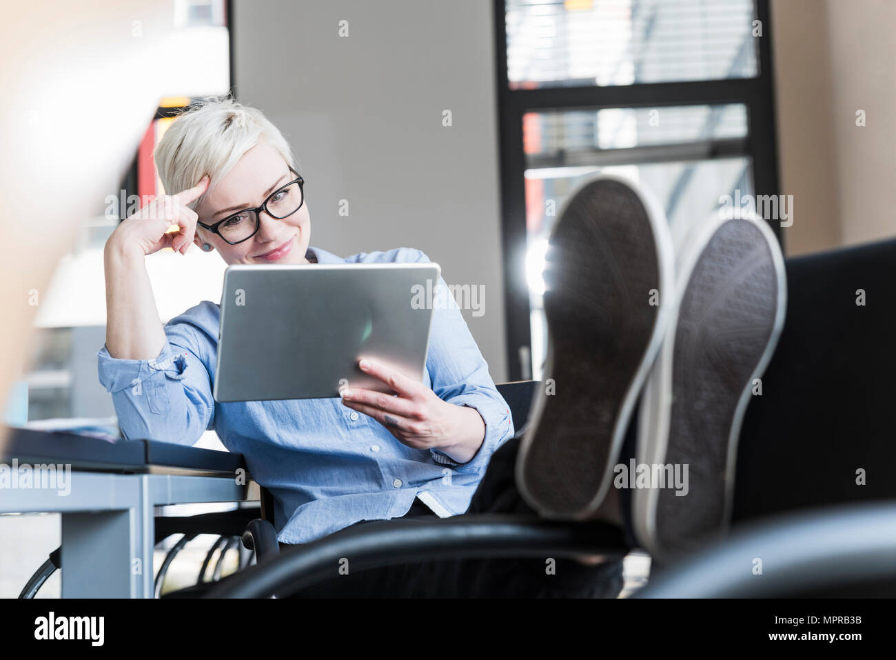 Smiling woman using tablet in office Stock Photo