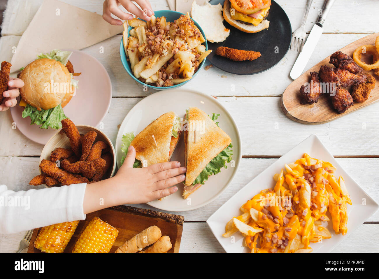 Children's hands on table full of American food Stock Photo
