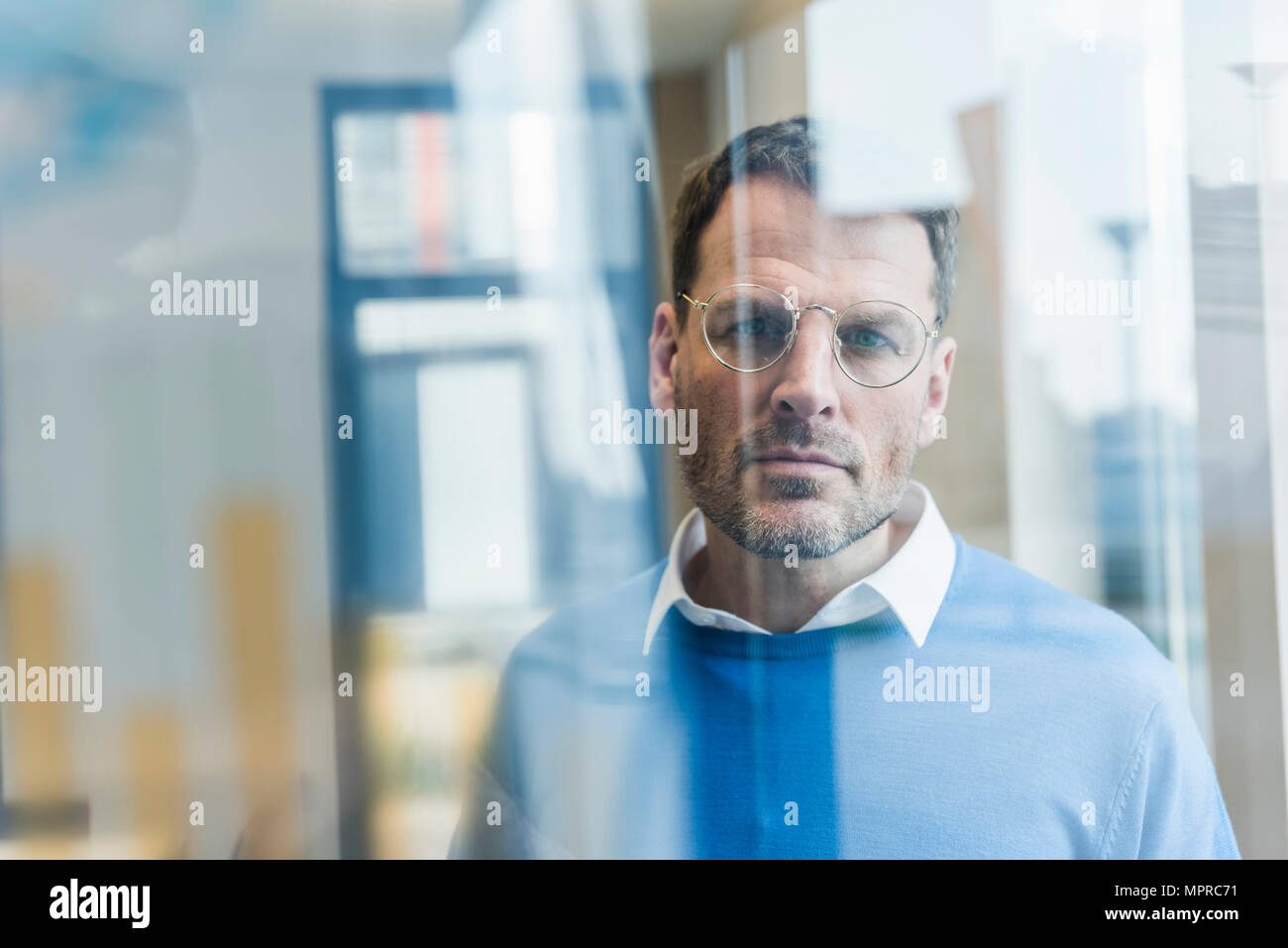 Focused businessman looking at glass pane Stock Photo