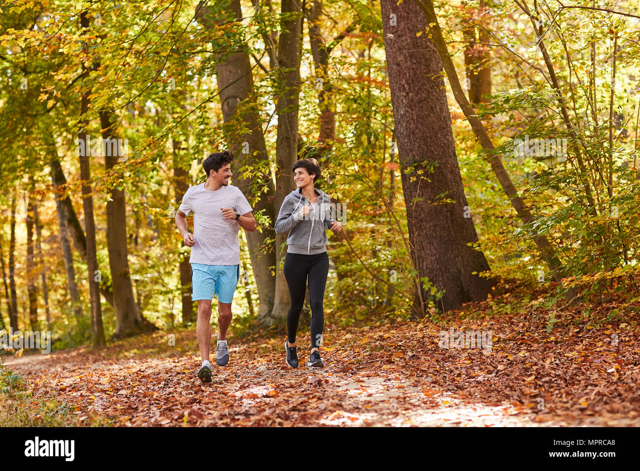 Couple jogging on autumnally forest track Stock Photo