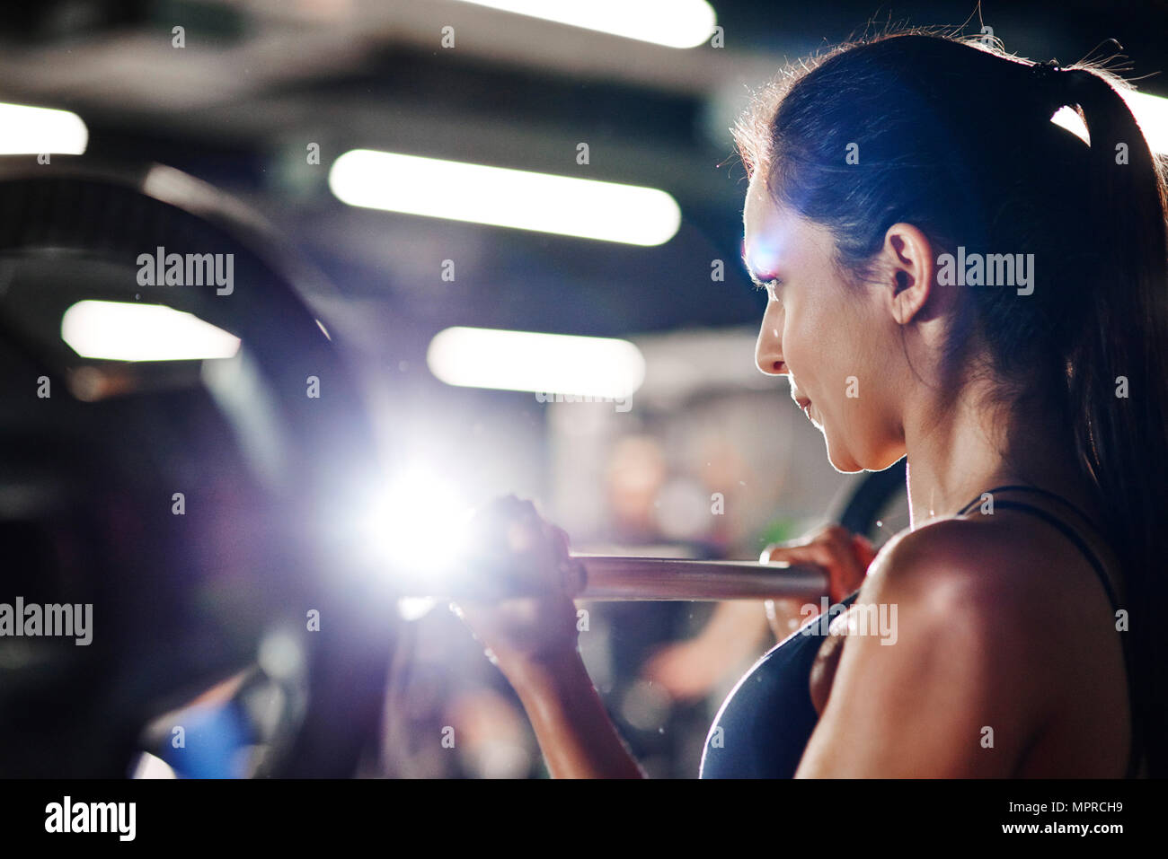 Woman lifting barbell in gym Stock Photo