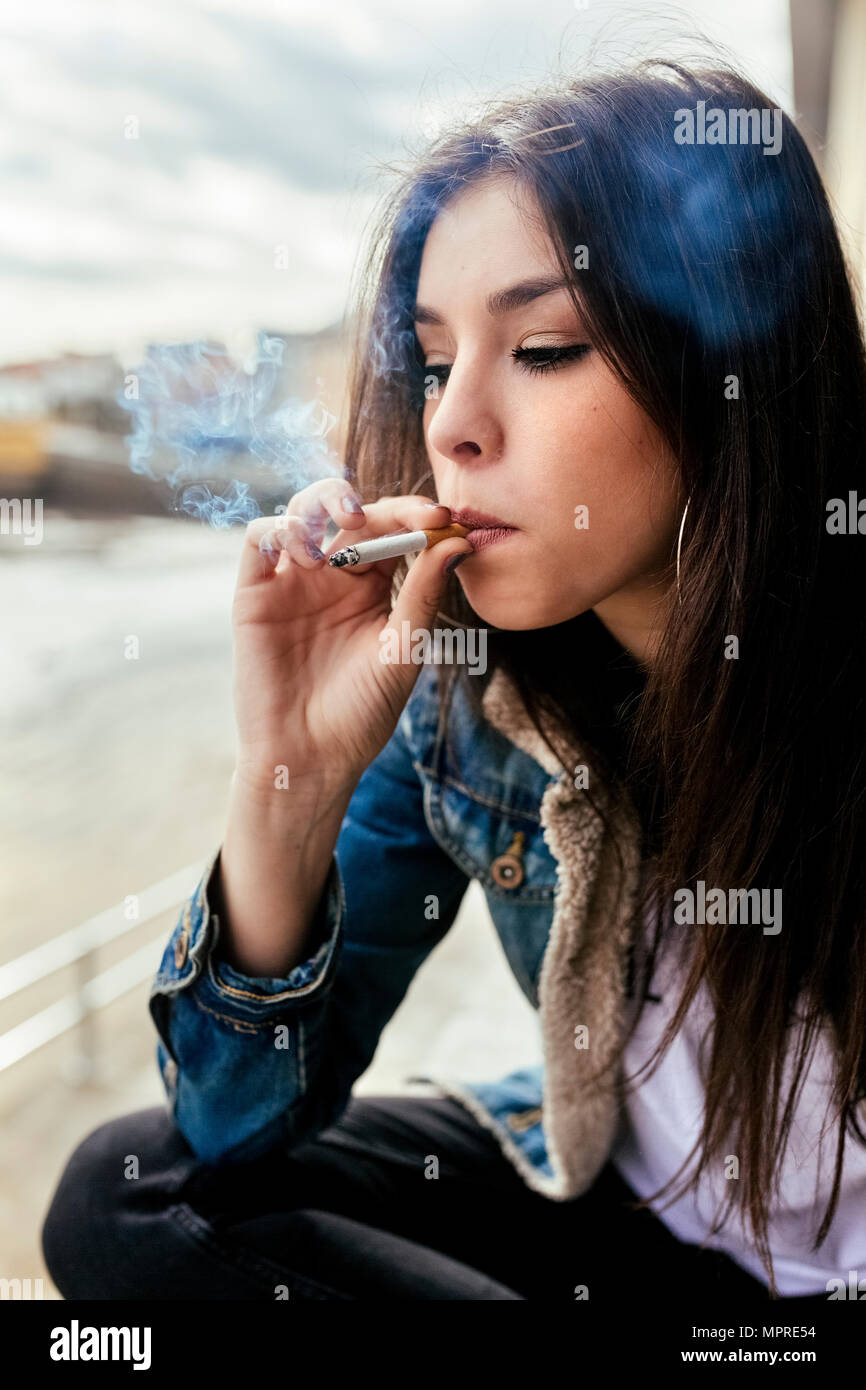Young woman smoking a cigarette outdoors Stock Photo