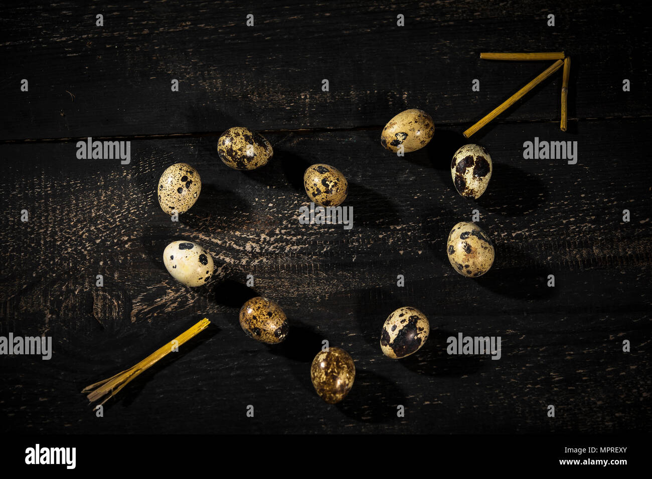 Quail eggs shaped as a heart and  arrow made of straw on dark wood Stock Photo