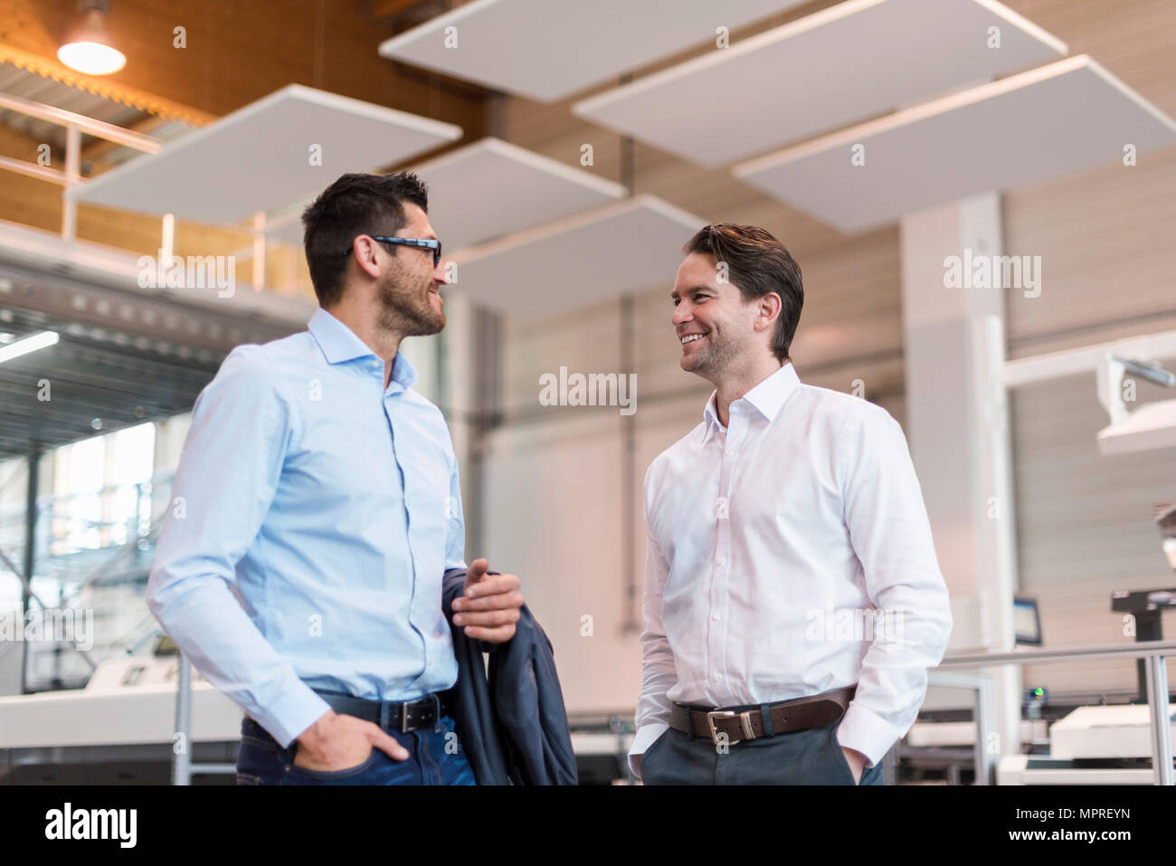 Two smiling businessmen talking in modern factory Stock Photo - Alamy
