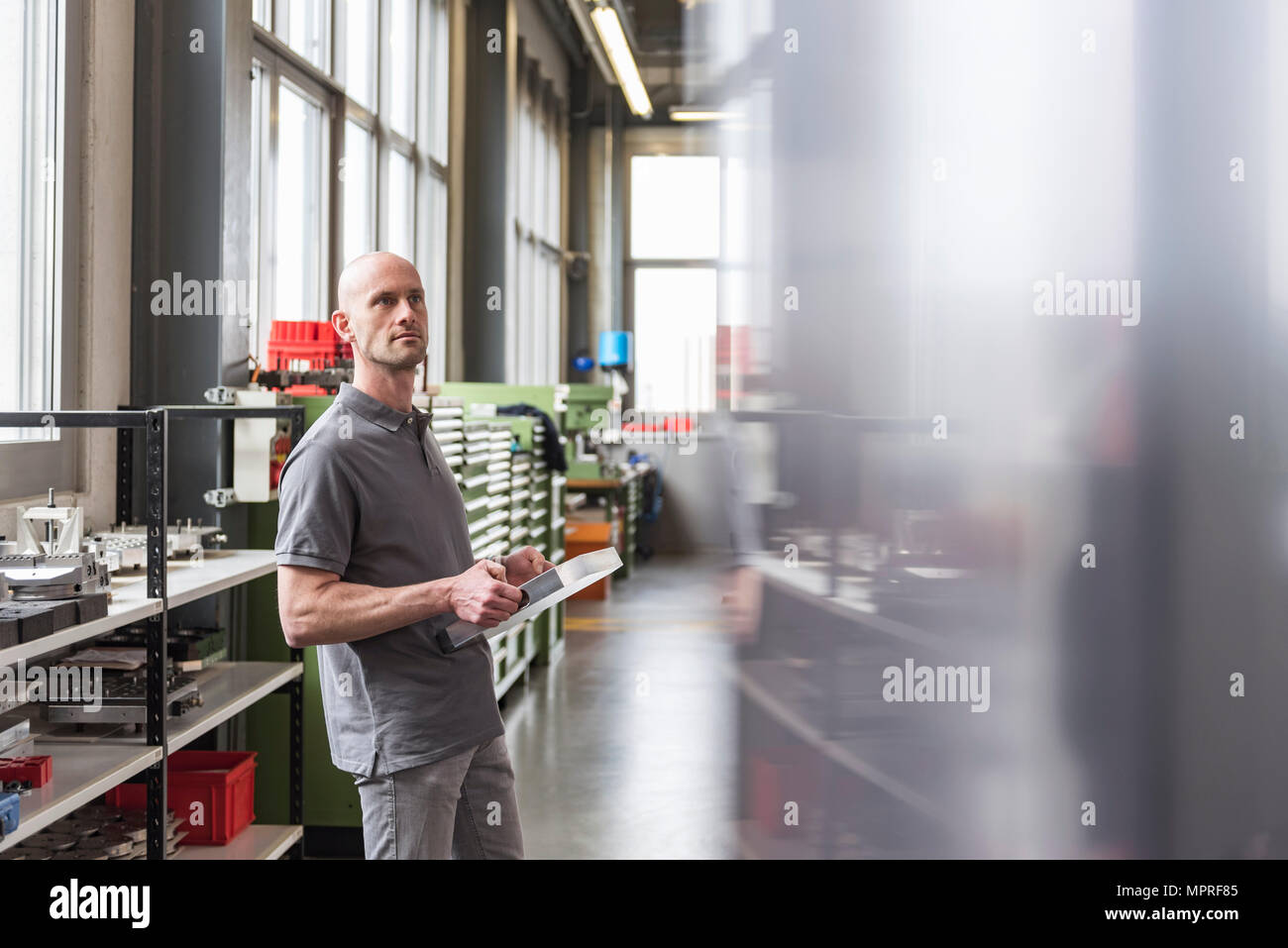 Man standing in modern factory holding product Stock Photo