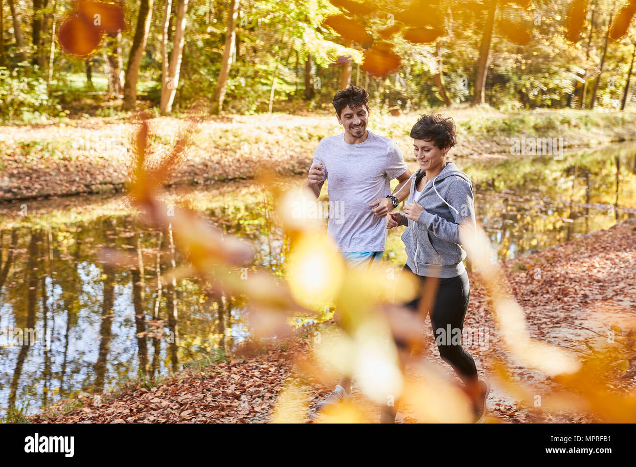 Couple jogging on autumnally forest track Stock Photo