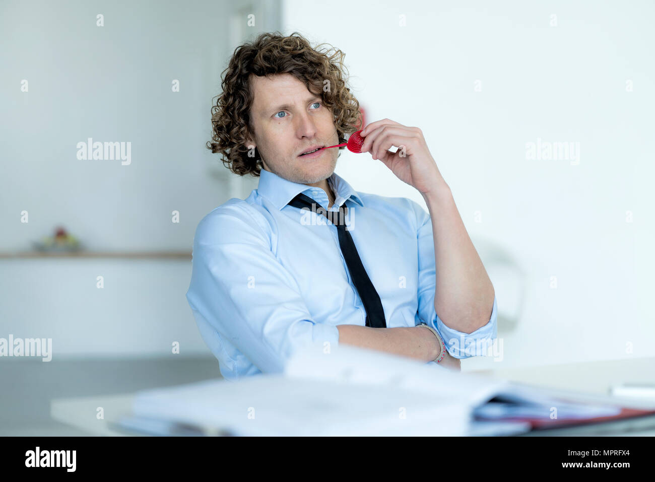 Easygoing businessman sitting in office, chewing sweets Stock Photo
