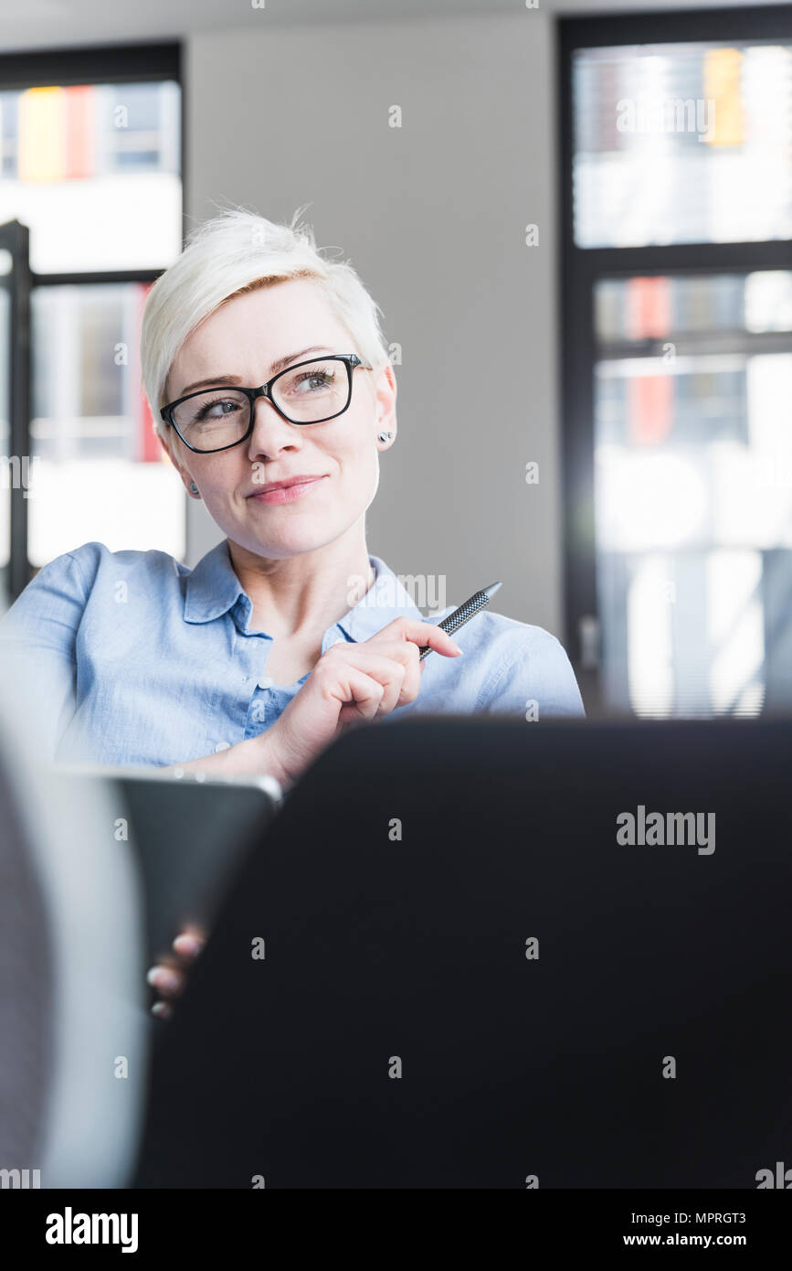 Portrait of smiling woman wearing glasses in office Stock Photo
