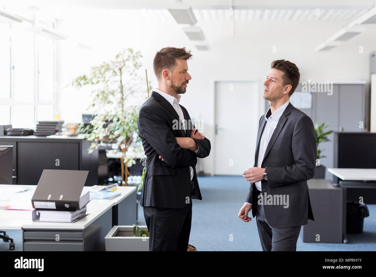 Two businessmen standing in office, discussing solutions Stock Photo