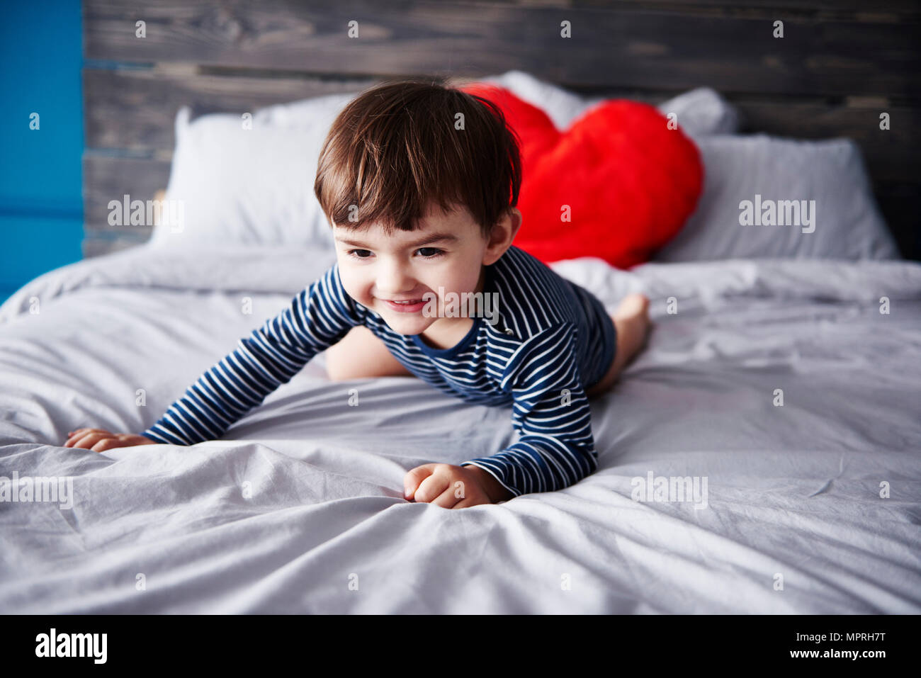 Portrait of smiling toddler crouching on bed Stock Photo