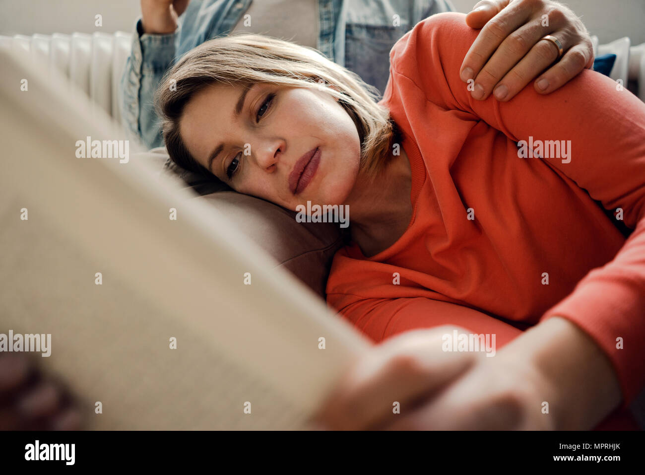 Happy couple reading and cuddling at home Stock Photo