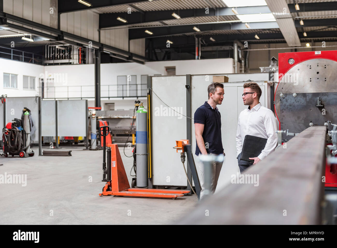 Two men standing and talking on factory shop floor Stock Photo - Alamy