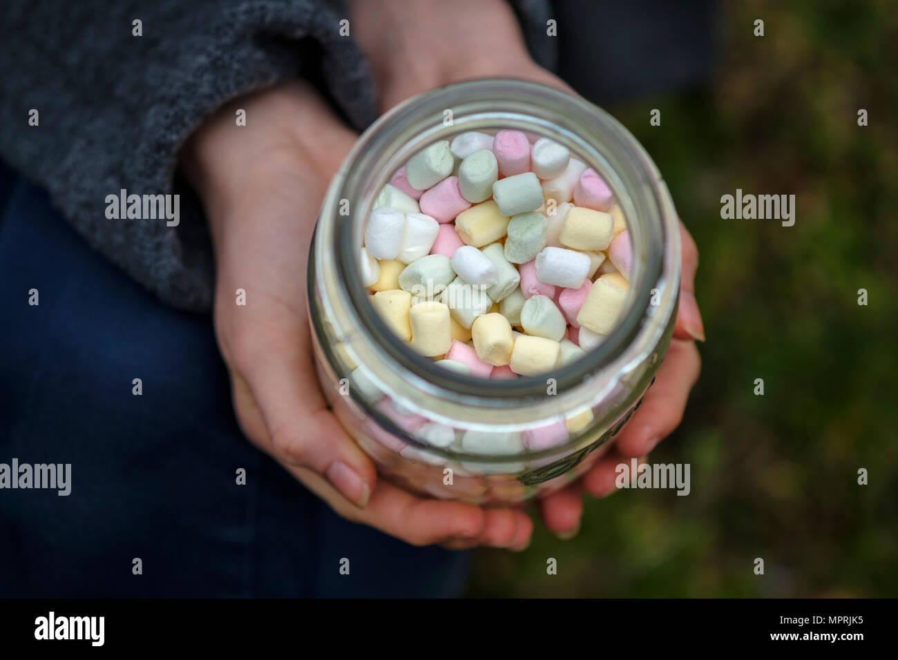 Hands holding glass of marshmallows, close-up Stock Photo
