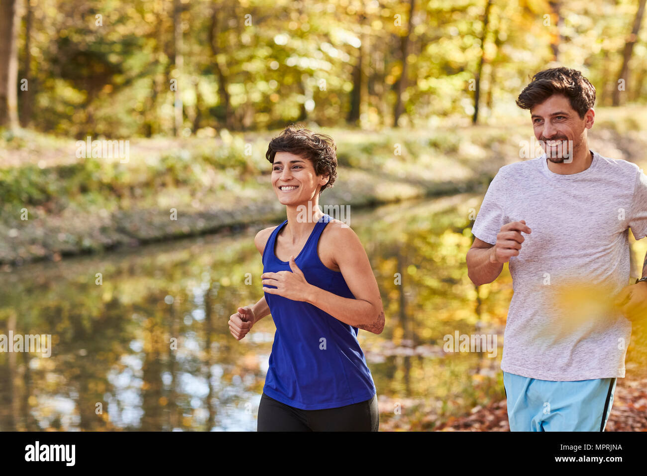 Couple jogging on autumnally forest track Stock Photo