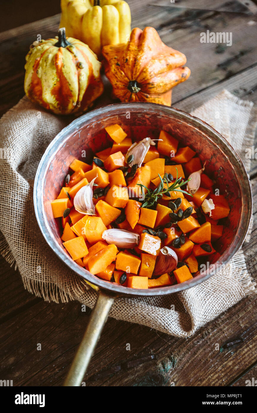 Diced pumpkin, garlic, rosemary and pumpkin seed in casserolle Stock Photo