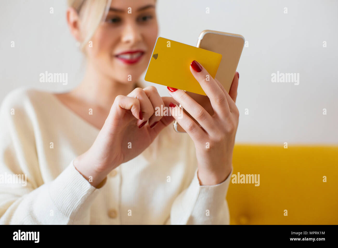 Woman using smartphone and using bank card at home Stock Photo