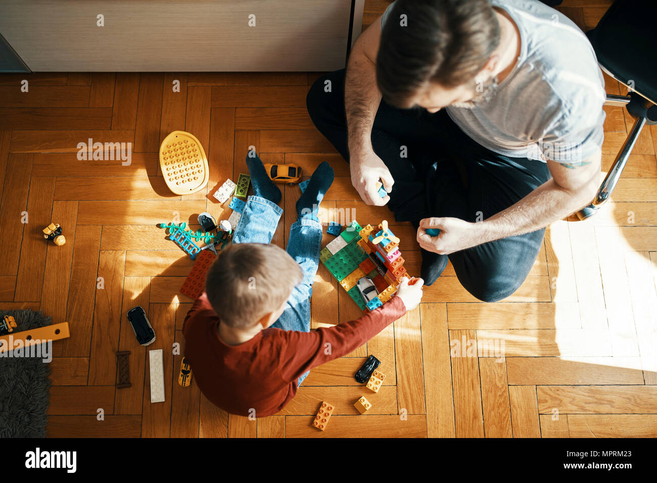 Father And Son Sitting On The Floor Playing Together With Building