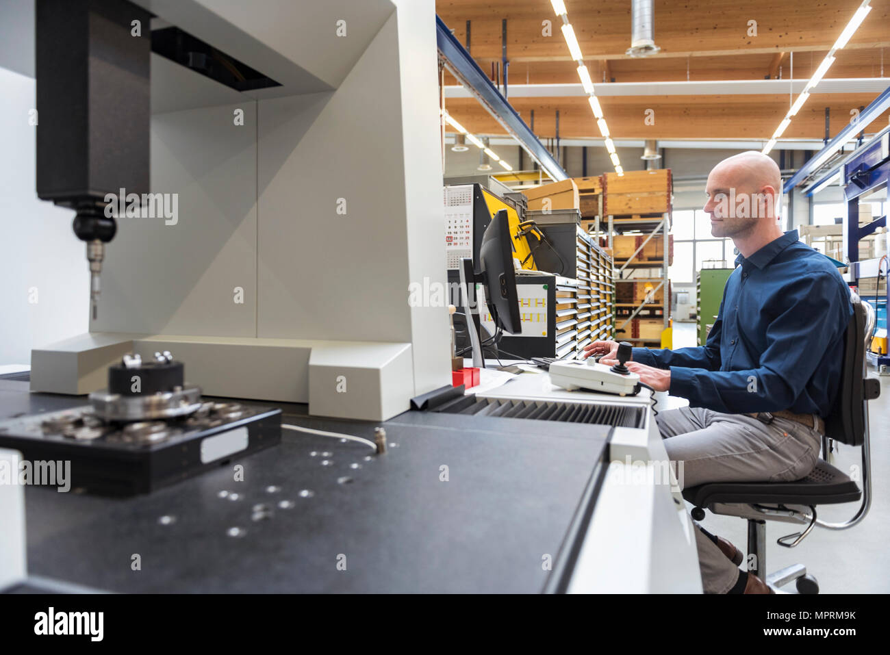 Man using computer at machine in modern factory Stock Photo