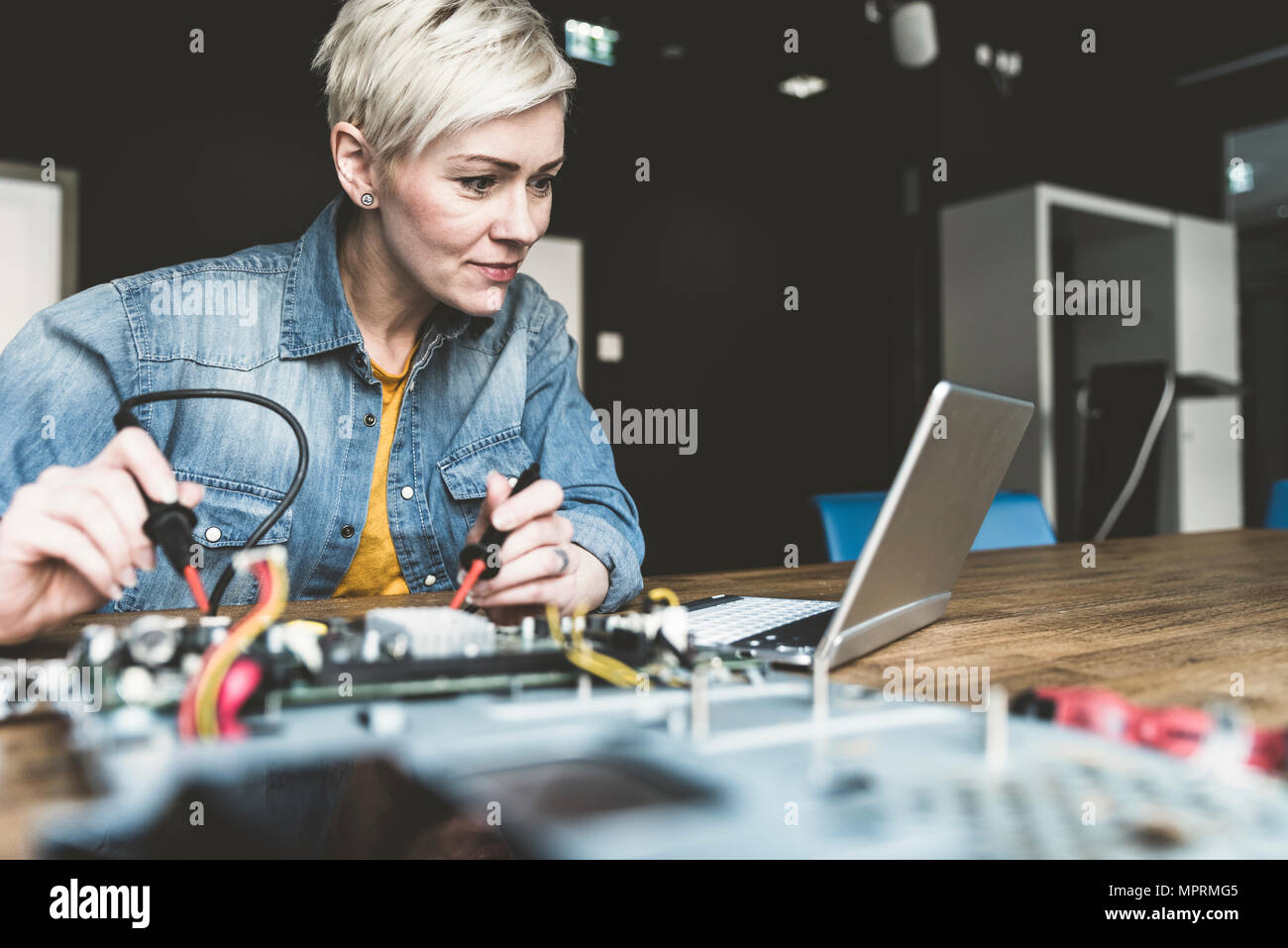 Woman working on computer equipment looking at laptop Stock Photo