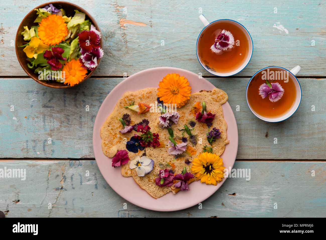 Pancake with edible flowers, pumpkin flower, Calendula, Chamaemelum nobile, Dianthus, Taraxacum officinale, Viola, Rosmarinus officinalis on bamboo pl Stock Photo